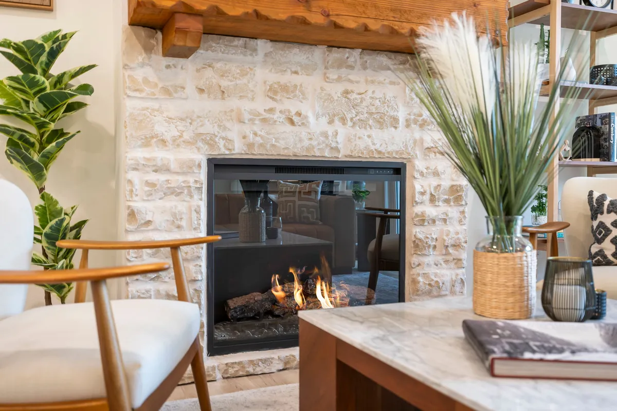 A fireplace nook featuring a cozy fire, coffee table, potted plant, and a decorative vase. The intimate setup is perfect for reading, relaxing, or connecting with loved ones by the fire.