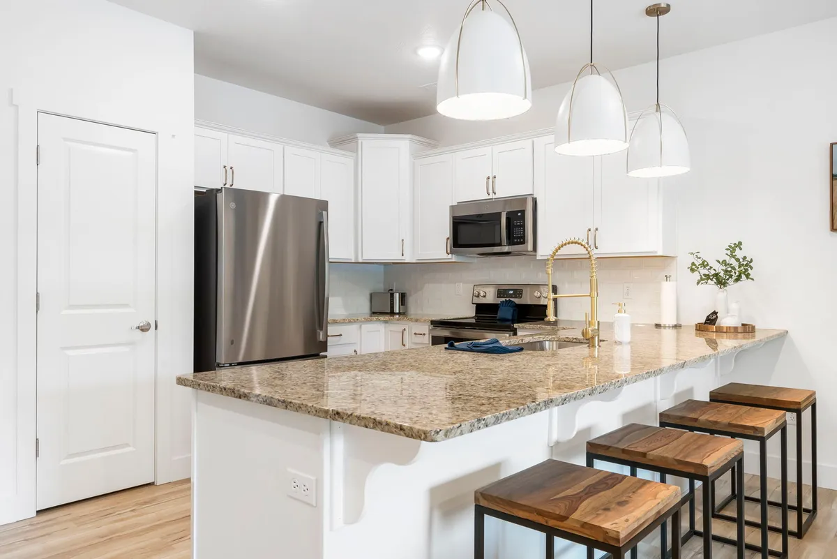 A bright, modern kitchen with a granite countertop, stylish pendant lights, and stainless steel appliances. The space exudes a welcoming ambiance ideal for both culinary adventures and casual dining.