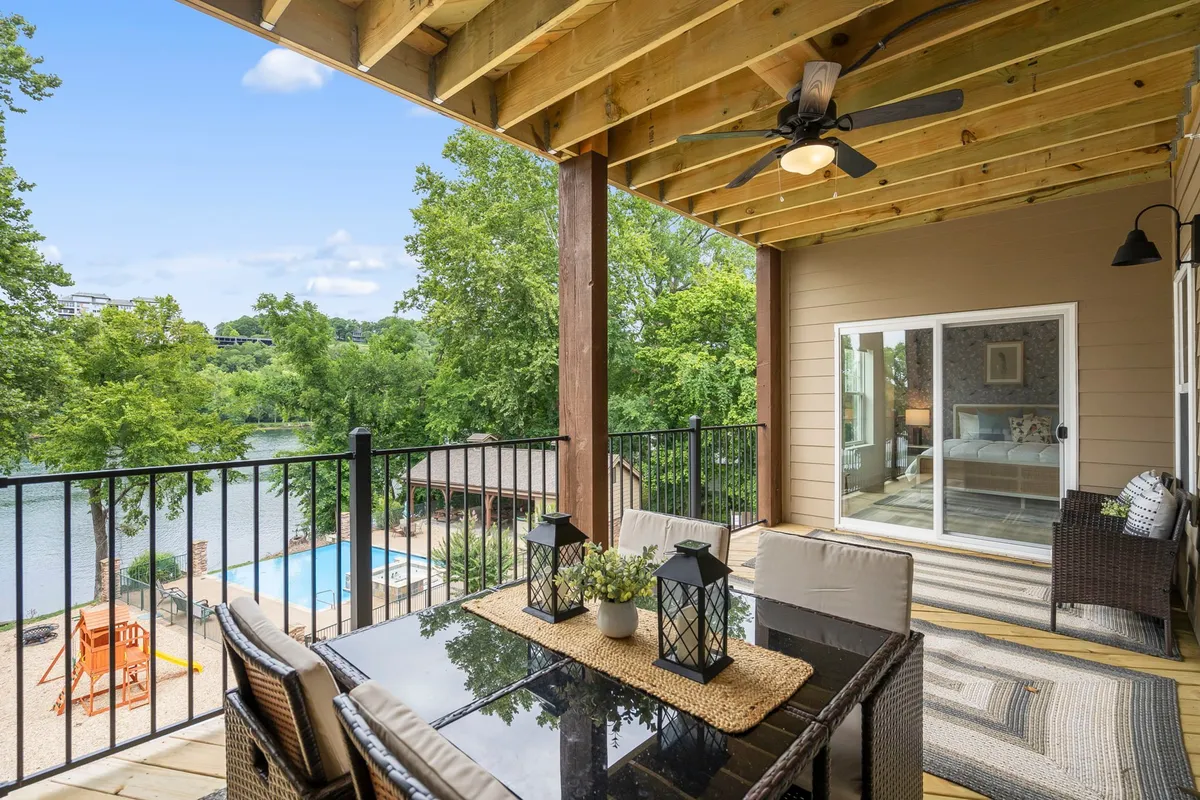 An inviting outdoor dining area with lantern-lit table, overlooking the river, swimming pool, and lush greenery. The space is set for alfresco meals and relaxed gatherings amid beautiful views.