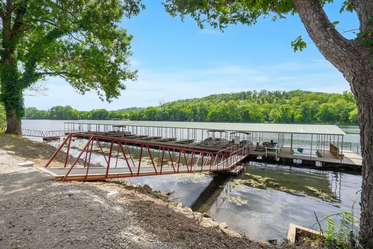 This serene exterior shot features a red dock extending over calm water, surrounded by lush greenery. The setting invites families to fish, boat, or simply take in the tranquil lake atmosphere together, perfectly matching the idea of morning strolls to the fishing dock described in the section.