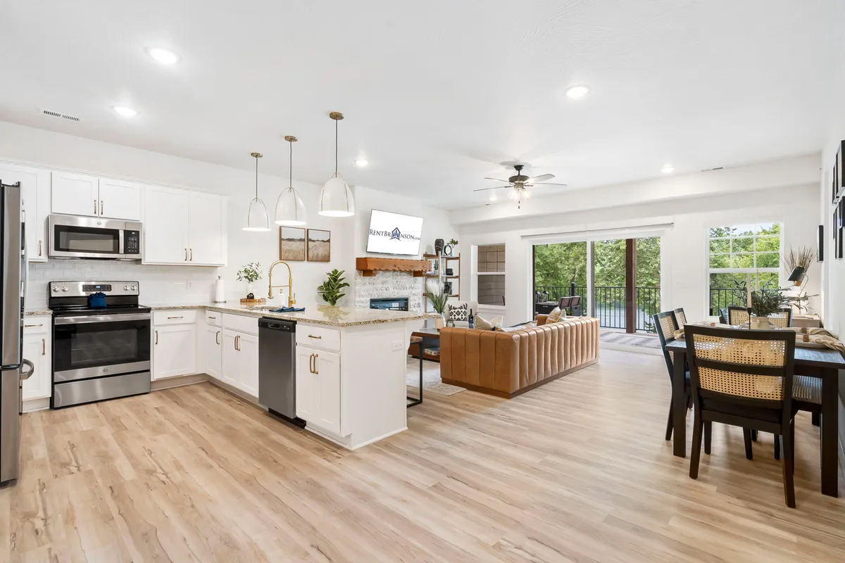 This image features a spacious, open-concept interior that seamlessly connects the kitchen island, dining table, and a comfortable sofa. Natural light fills the room, and the arrangement encourages gathering, socializing, and shared meals.